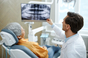 レントゲン写真を指して説明する男性歯科医師