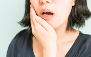歯の痛みを耐えて顎を抑える女性