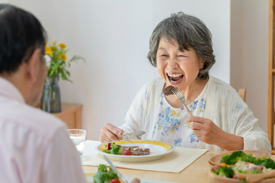 自費入れ歯で美味しくステーキを食べる女性