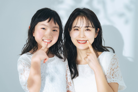 笑顔で歯を見せ指さす親子
