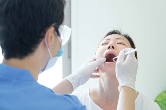 横向きに生えた親知らずを抜くために歯科医に診察してもらう患者