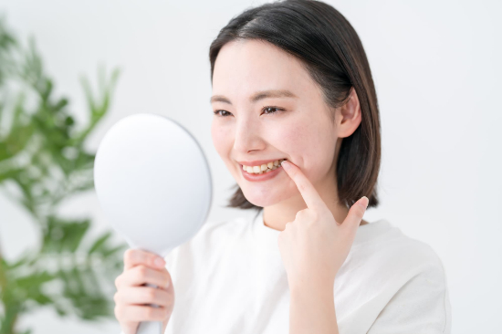鏡を見て歯並びが整ってきたことを実感して喜ぶ女性